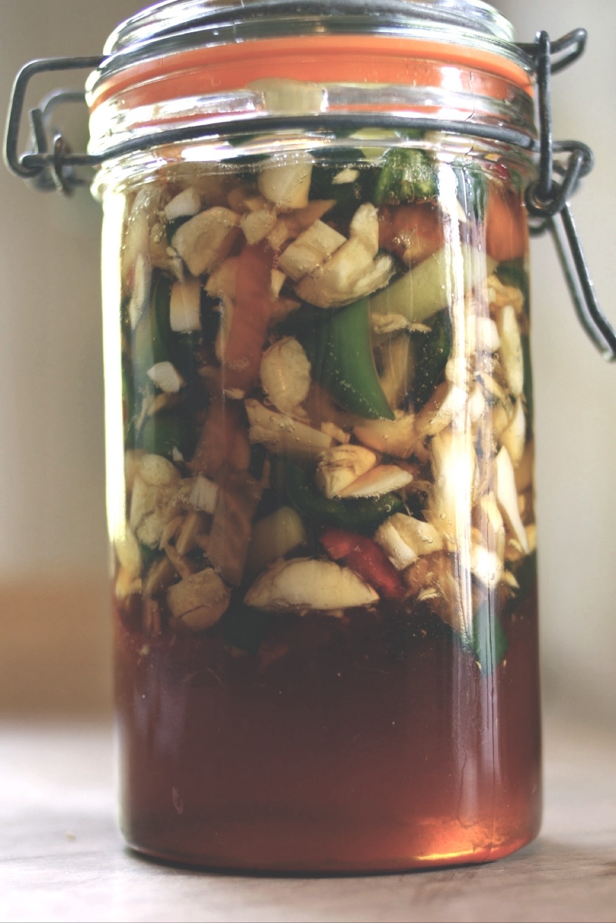 Finished jar of fermented garlic jalapeño honey, golden and runny with peppers and garlic, ready to use